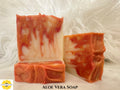 Aloe Vera Soap - Three orange and white soap bars on a textured white background with Sunlit Soaps branding,