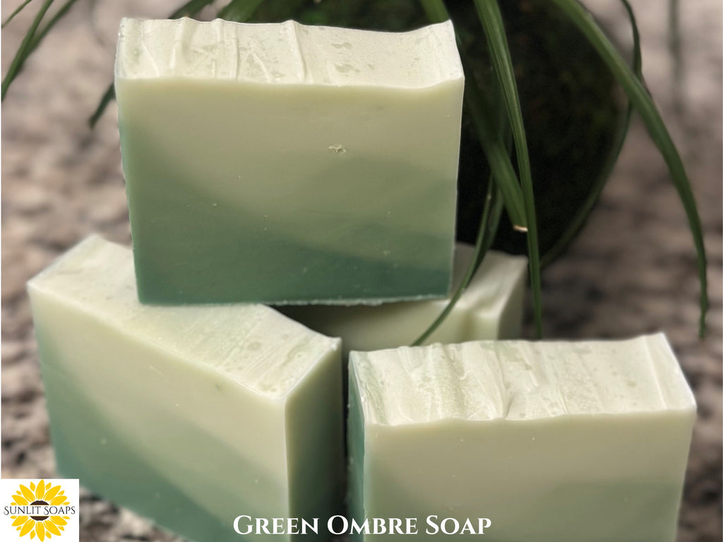 Green ombre soap bars with a plant in the background, Sunlit Soaps logo in the corner