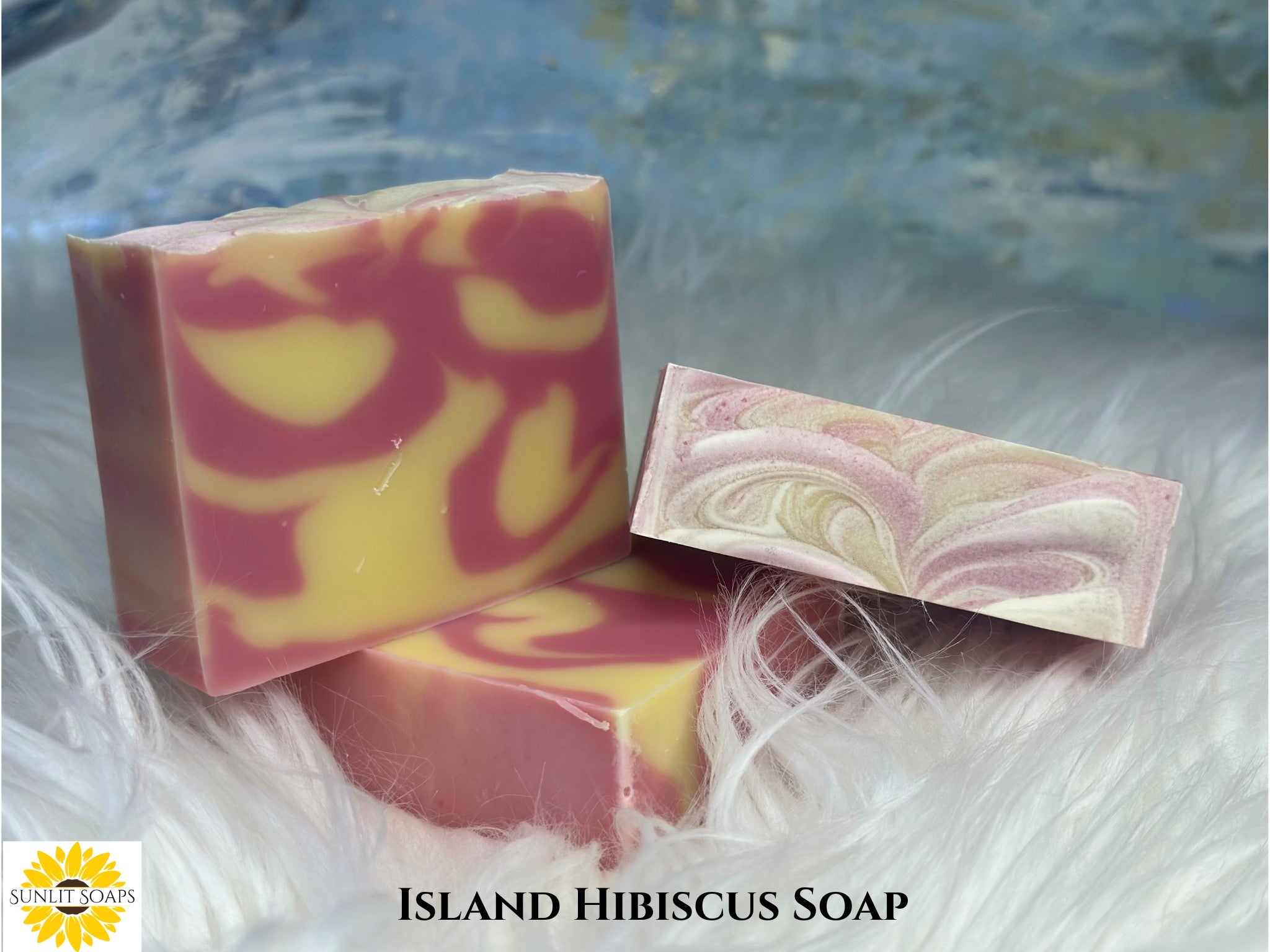 Two bars of Island Hibiscus soap with a marbled design on a textured surface with Sunlit Soaps branding.