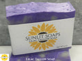 Bar of lilac tallow soap with Sunlit Soaps label on a gray background