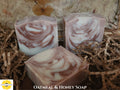 Three bars of oatmeal and honey soap on a textured surface with 'Sunlit Soaps' branding.