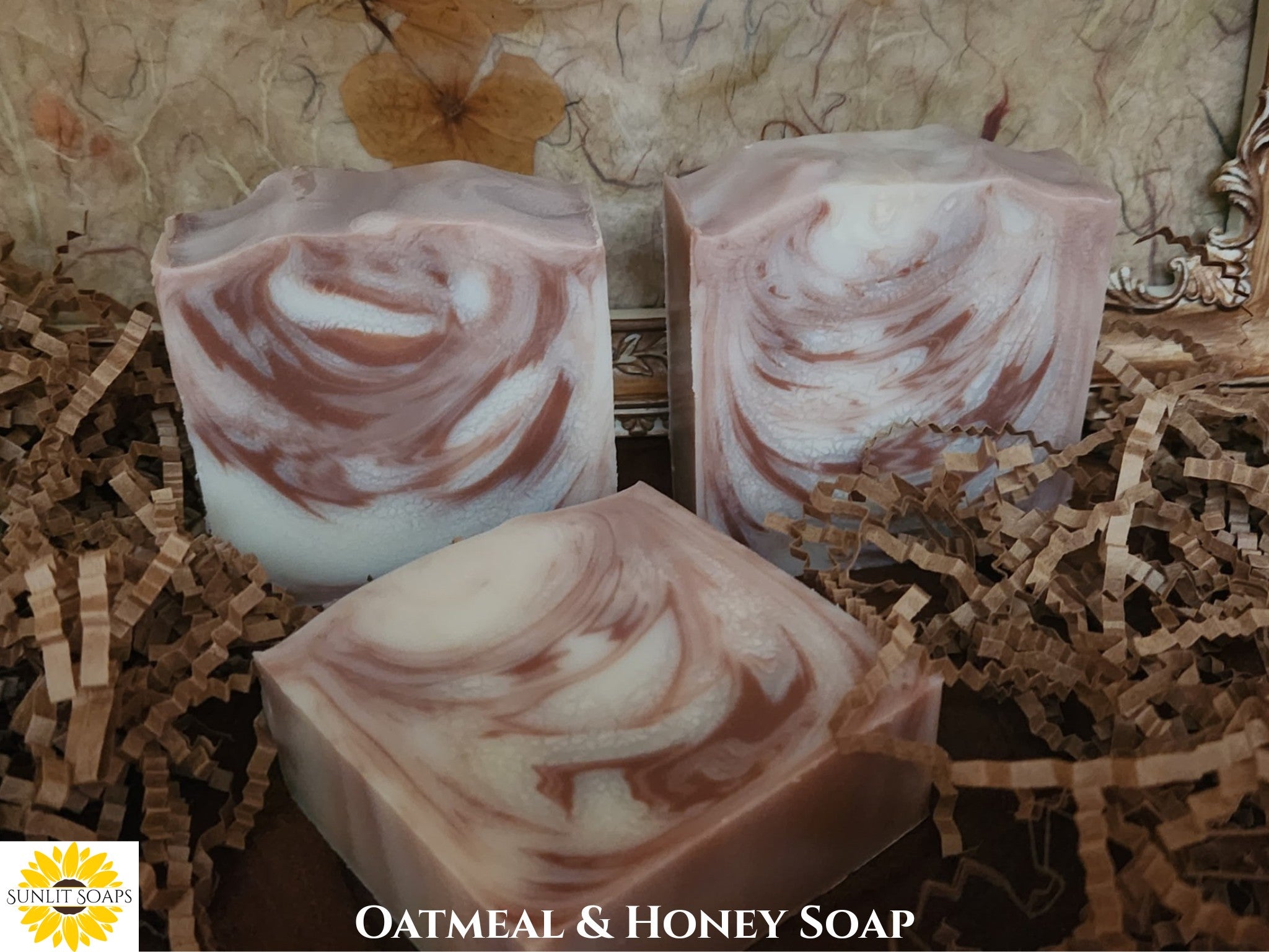 Three bars of oatmeal and honey soap on a textured surface with 'Sunlit Soaps' branding.