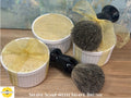 Shave soap in white containers with two brushes on a wooden surface, featuring 'Sunlit Soaps' branding.